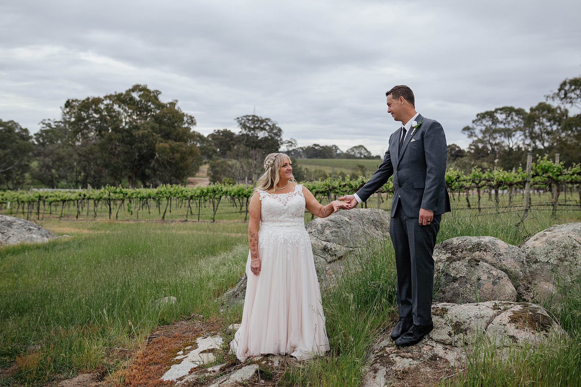 Bride & Groom couple shoot on rock formation with vineyards behind them. 