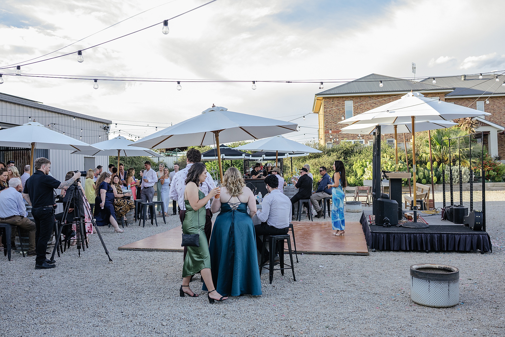 Outdoor wedding reception with umbrellas and bistro lights.