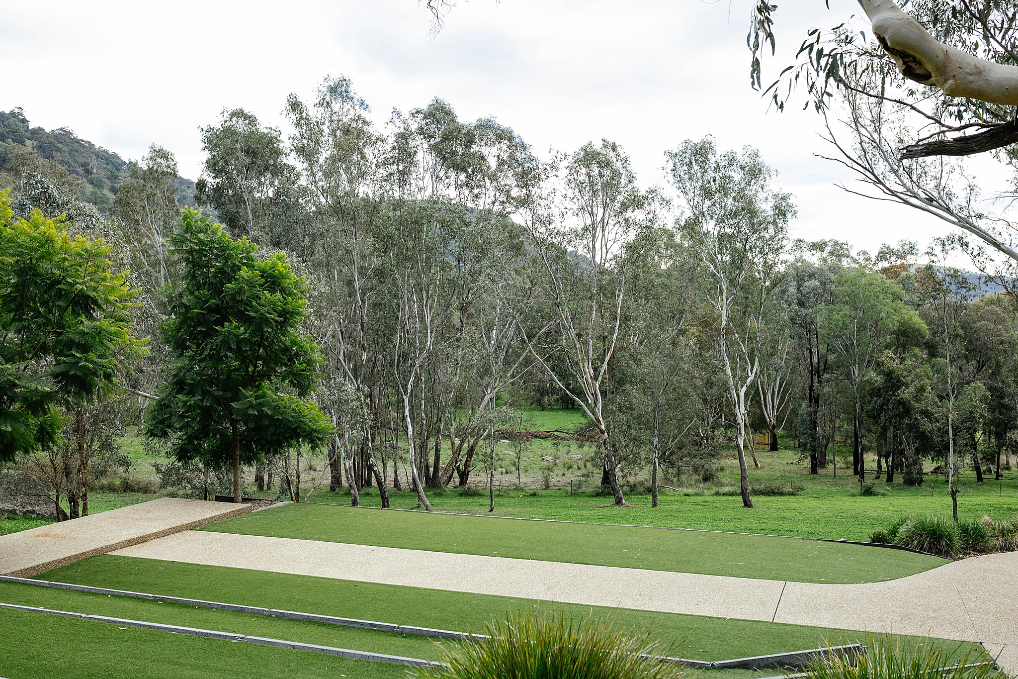 Outdoor wedding ceremony space featuring tiered lawn terraces with retaining walls, allowing guests to sit on different elevations overlooking the ceremony area.